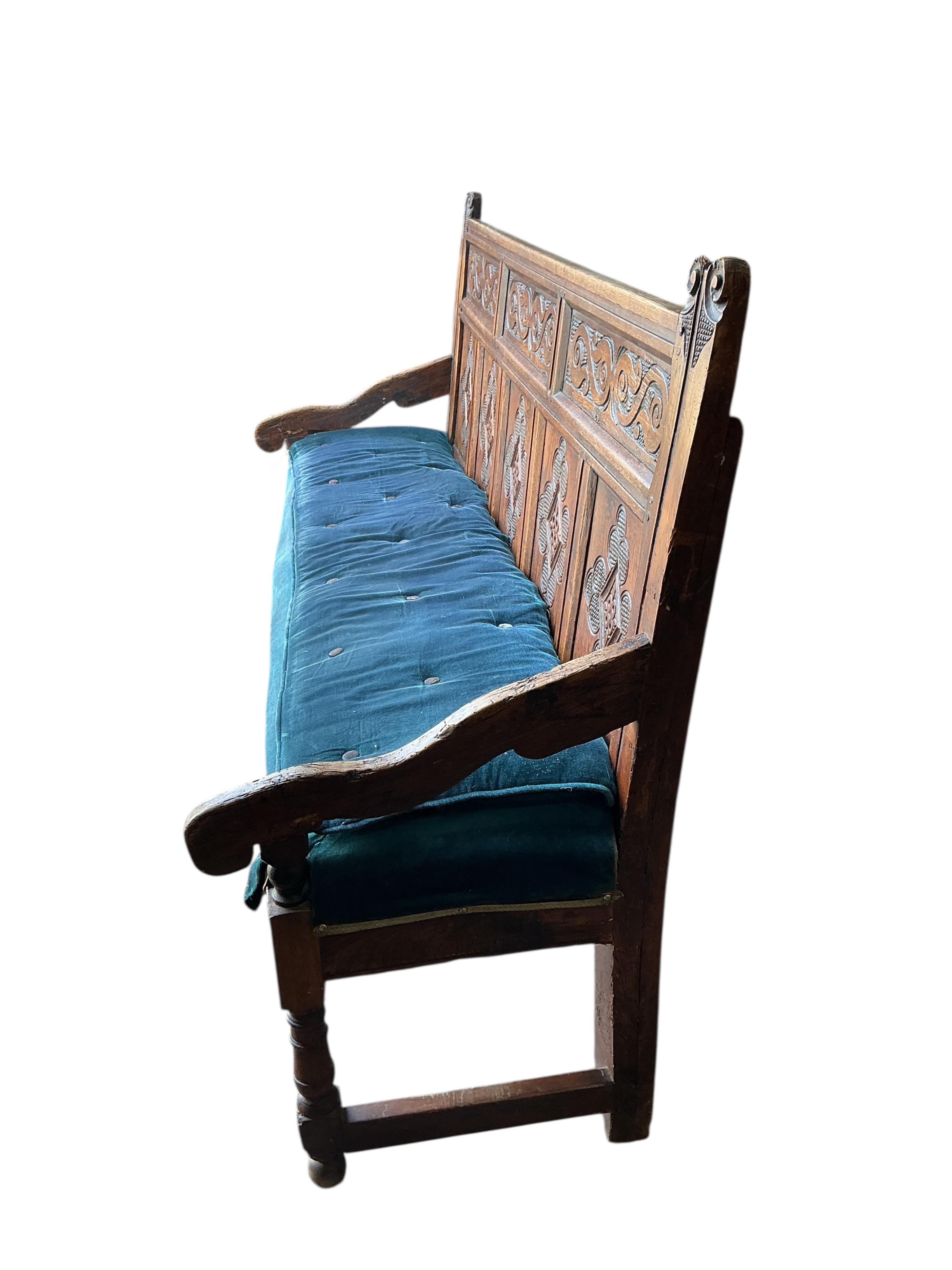 An 18th century panelled oak settle, later carved, width 177cm, depth 55cm, height 110cm